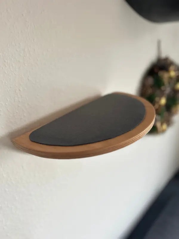 Halbkreisförmiges Holzregal mit schwarzer Oberfläche.