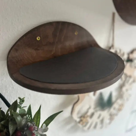 Katzenregal aus Holz mit dunklem Kissen.