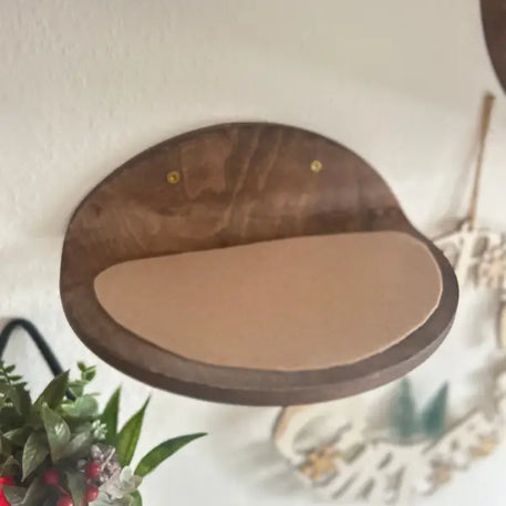 Wandmontiertes Katzenregal aus Holz mit braunem Kissen.