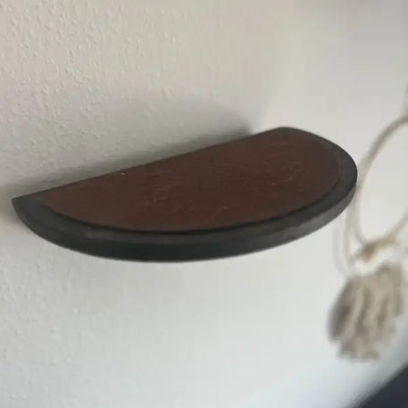 Halbkreisförmiges braunes Regal mit dunkler Verzierung.