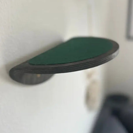 Wandmontiertes, halbrundes Katzenregal mit grünem Stoff.