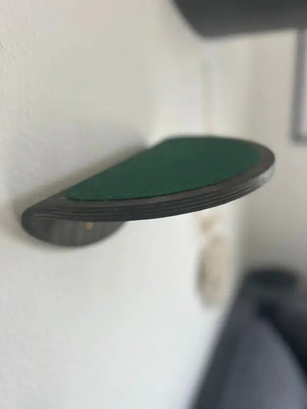Wandmontiertes, halbrundes Katzenregal mit grünem Stoff.