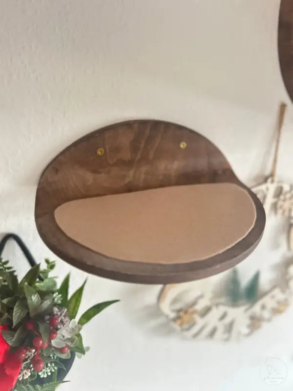 Wandmontiertes Katzenregal aus Holz mit braunem Kissen.