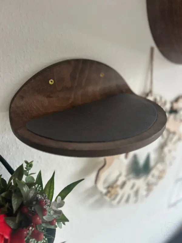 Katzenregal aus Holz mit dunklem Kissen.