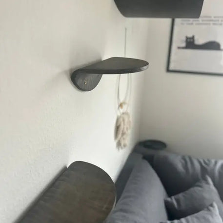 Drei dunkle Holzregale für Katzen.