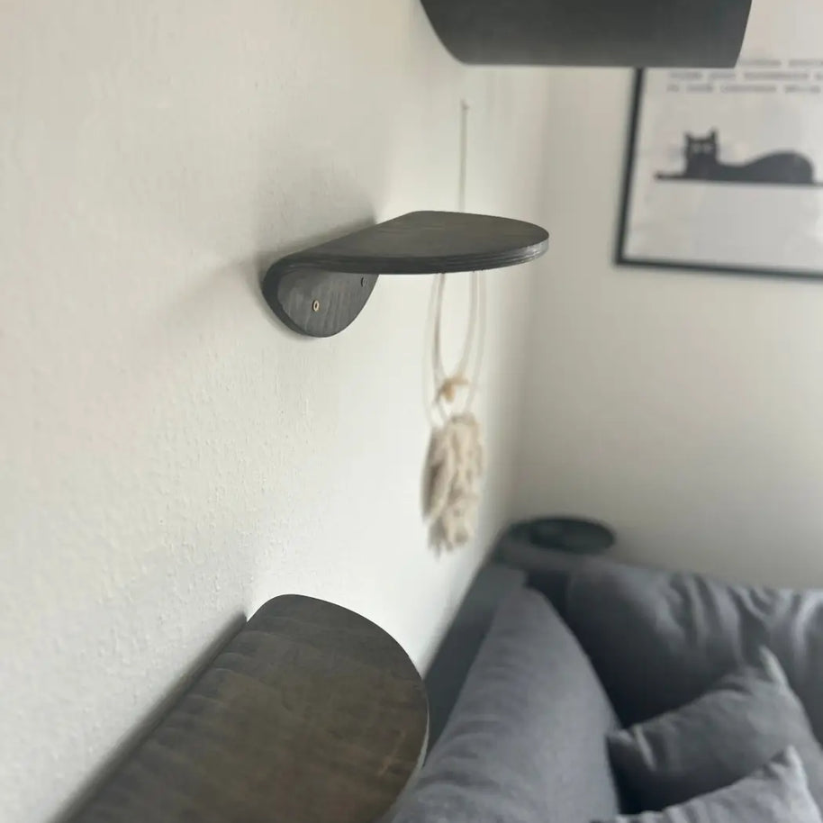 Drei dunkle Holzregale für Katzen.