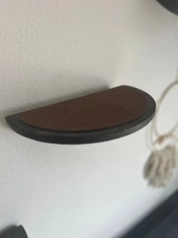 Halbkreisförmiges braunes Regal mit dunkler Verzierung.