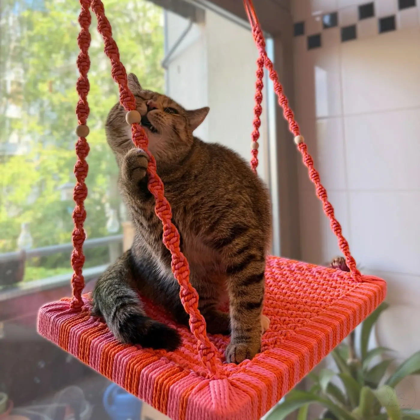 Eine lebhafte orange macrame katzenliege fensterplatz mit holzperlen aus der phinias fensterliege sommeredition
